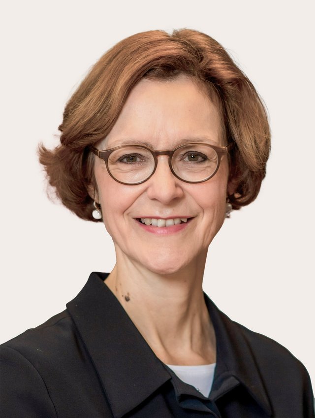 Ein Foto von Monika Rühl vor beigem Hintergrund.